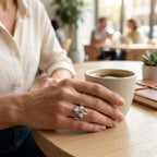 Anello trilogy sfalsato in argento 925 indossato sulla mano accanto a una tazza di caffè.