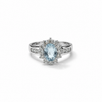 Anello in argento 925 con pietra ovale azzurra, contorno di pietre chiare e dettagli luminosi sul gambo, vista frontale.