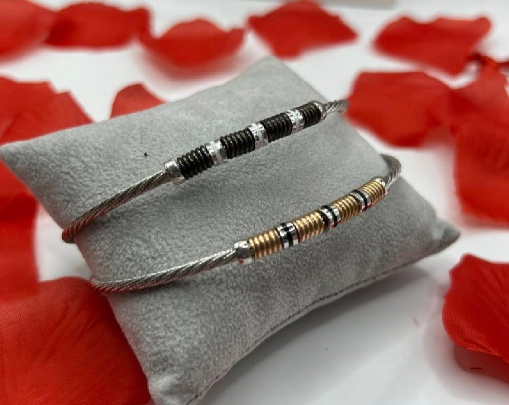 Bracciali rigidi in argento 925 e oro 18k, design moderno a cavo con dettagli cilindrici.