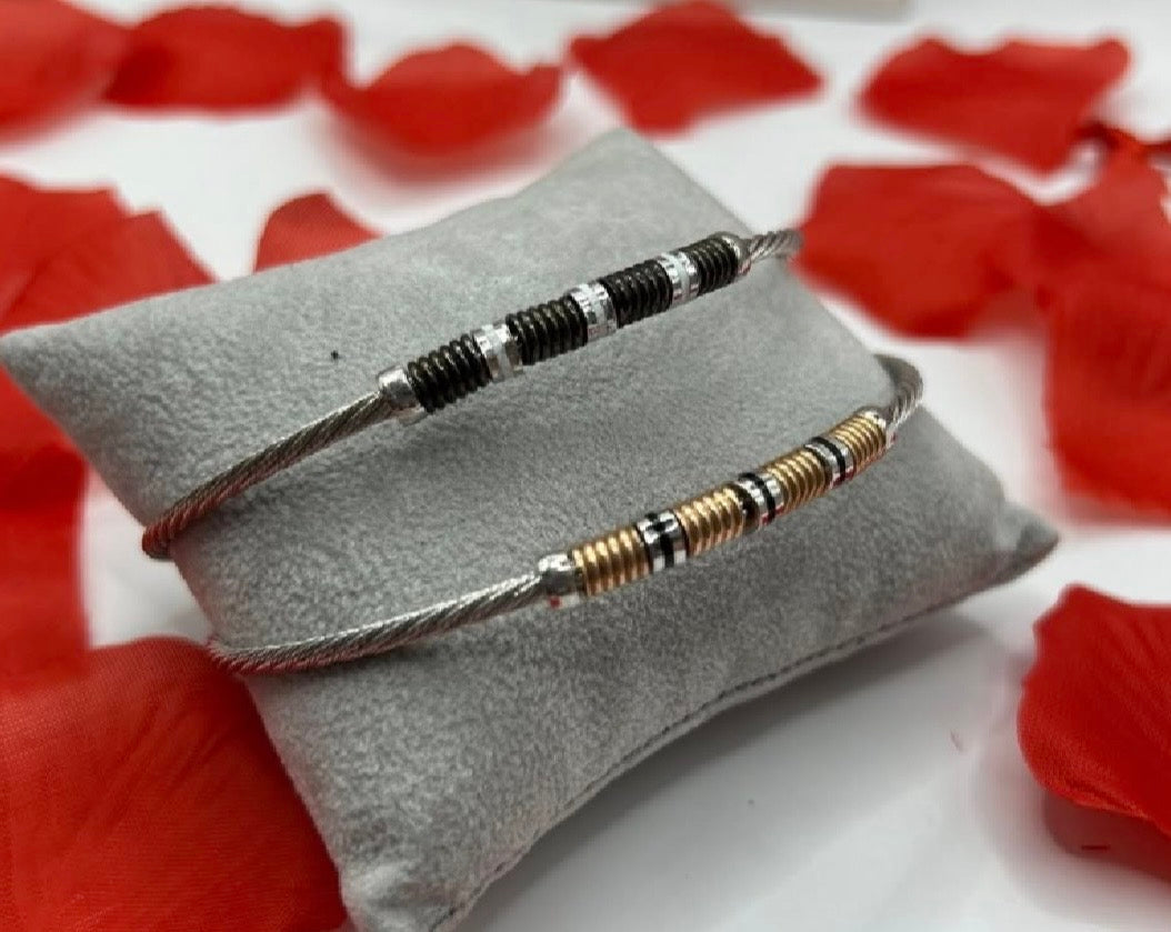 Bracciali rigidi in argento 925 e oro 18k, design moderno a cavo con dettagli cilindrici.