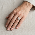 Anello in argento 925 con pietra rettangolare trasparente indossato all’anulare, con la mano appoggiata su tessuto chiaro.