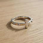 Anello rosario in argento 925 con croce e grani a sfera, vista da un angolo alternativo su superficie in legno